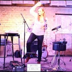 Kira Ludlow tanzt auf der Bühne vor einer Backsteinwand